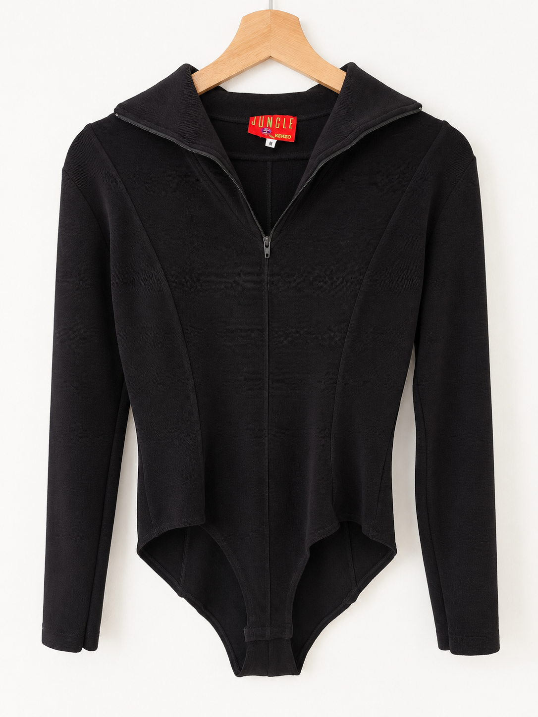 A black long-sleeve bodysuit with a mock neck and front zipper, hanging on a wooden hanger against a plain white background.